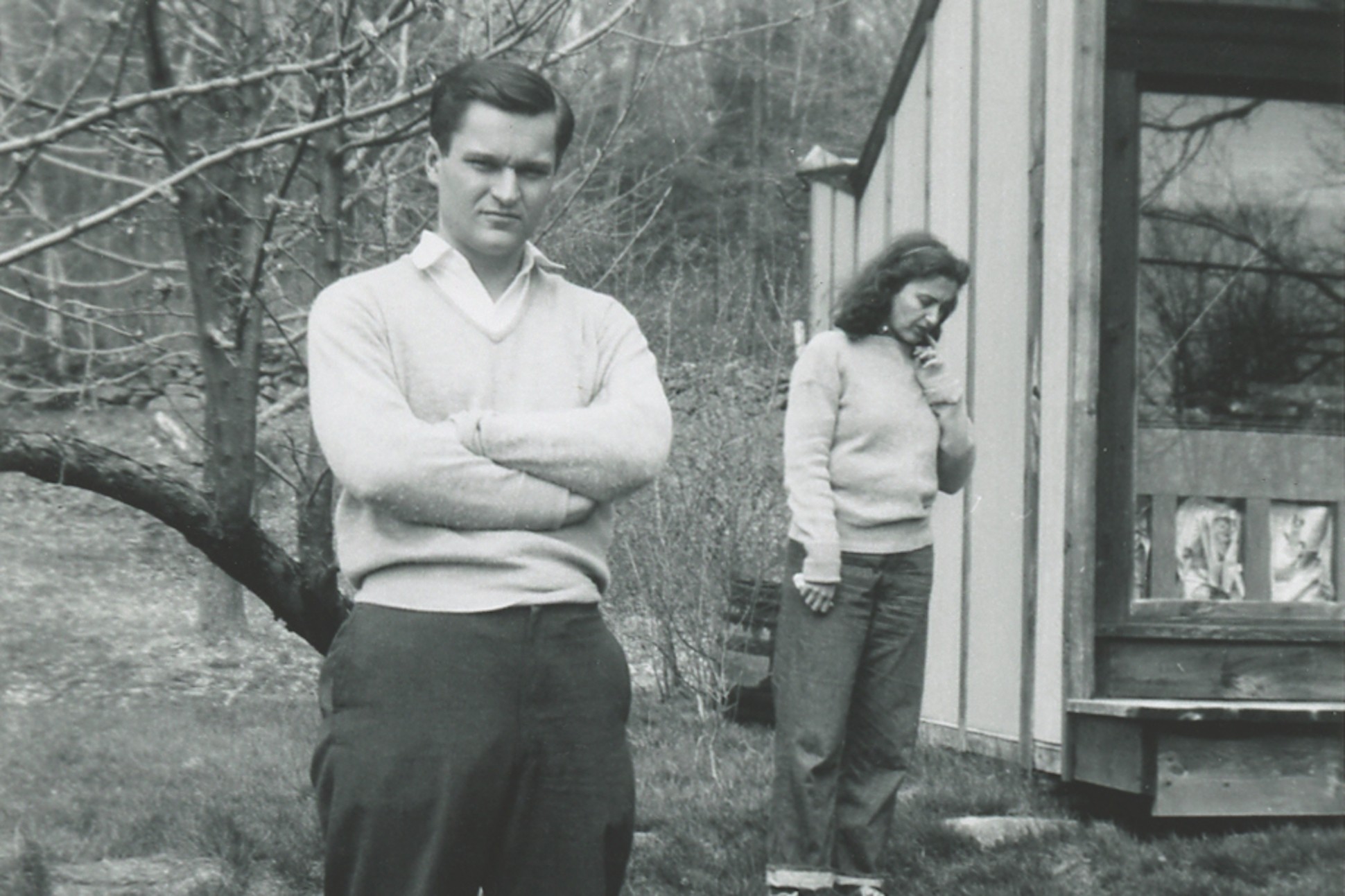 Black and white image of John Ashbery and Jane Freilicher standing near a building in Cornwall, Connecticut in 1954.
