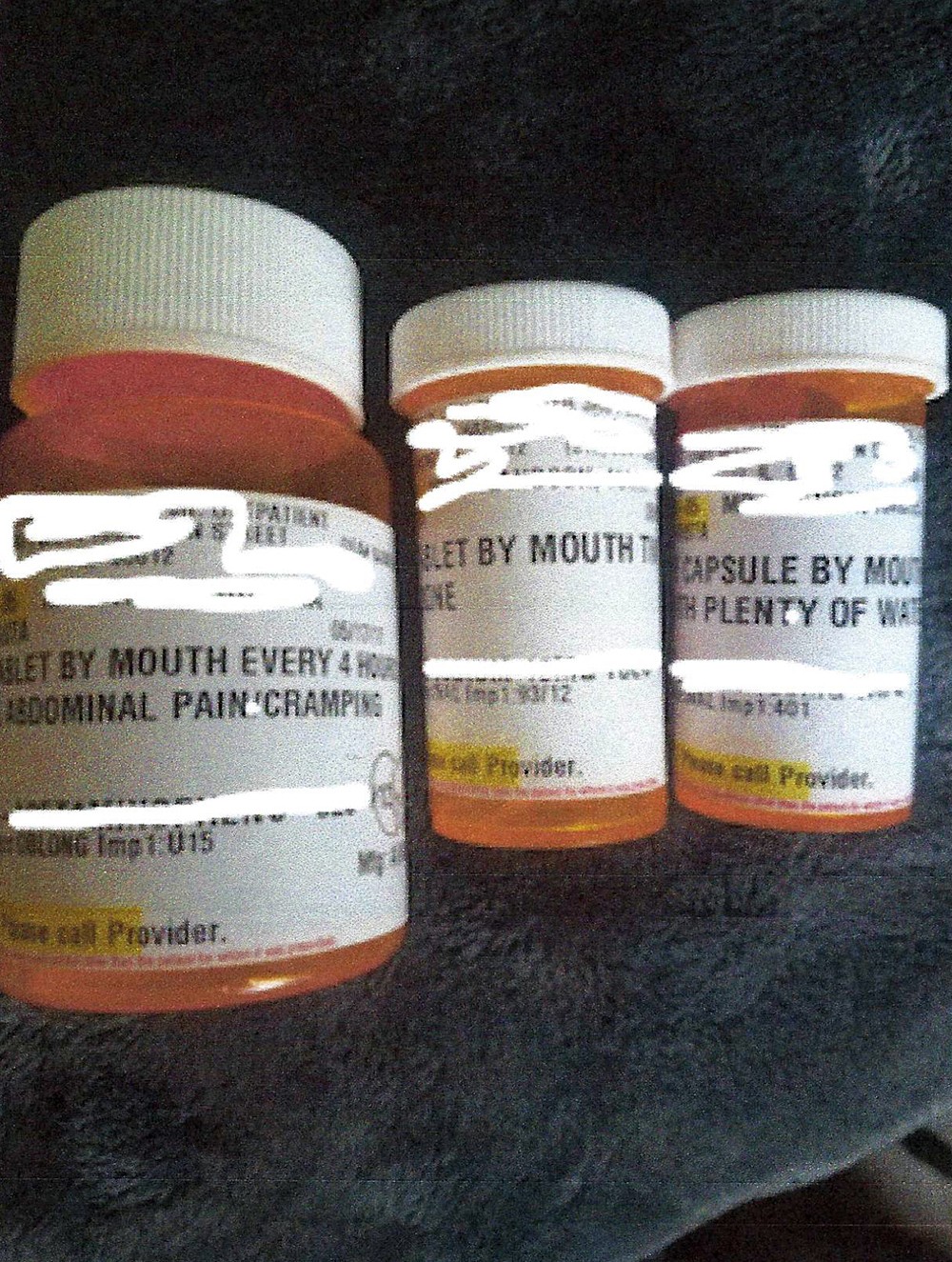 A photo of three prescription pill bottles with identifying information digitally redacted.