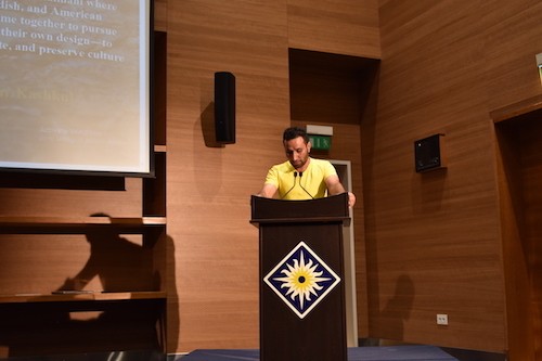 Ezidi poet Jaff reading at podium.