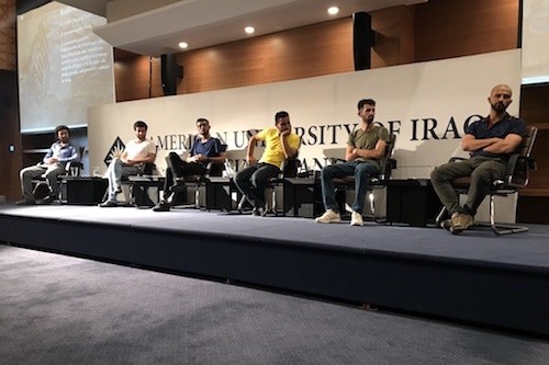 The six poets at the reading sit on stage as it begins. From R to L: Emad, Saad, Jaff, Zêdan, Sardan, Zaeem. Photo by Alana Marie Levinson LaBrosse.