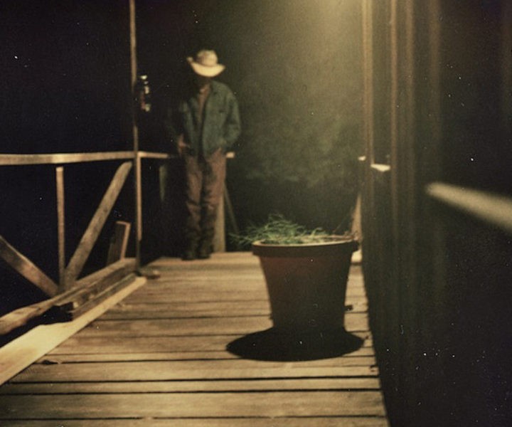 Mark Linkous, in cowboy at on porch at night. Photo by Gregg Greenwood.