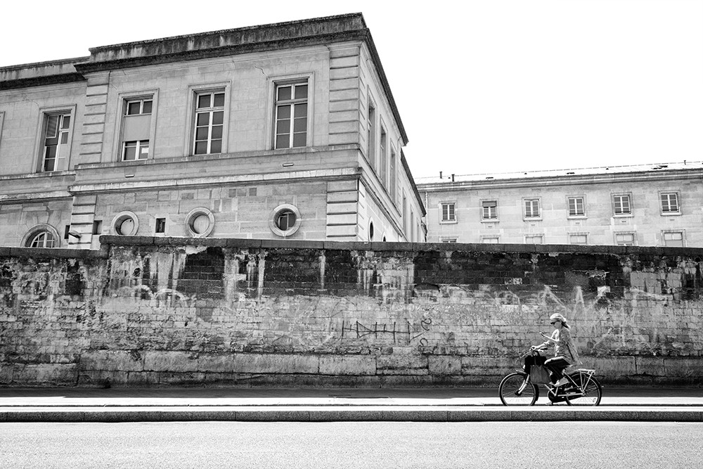 Photograph of graffiti on building with cyclist riding past.