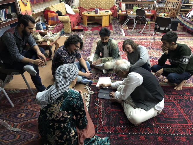 Pirbal sitting on the floor with students surrounding him.