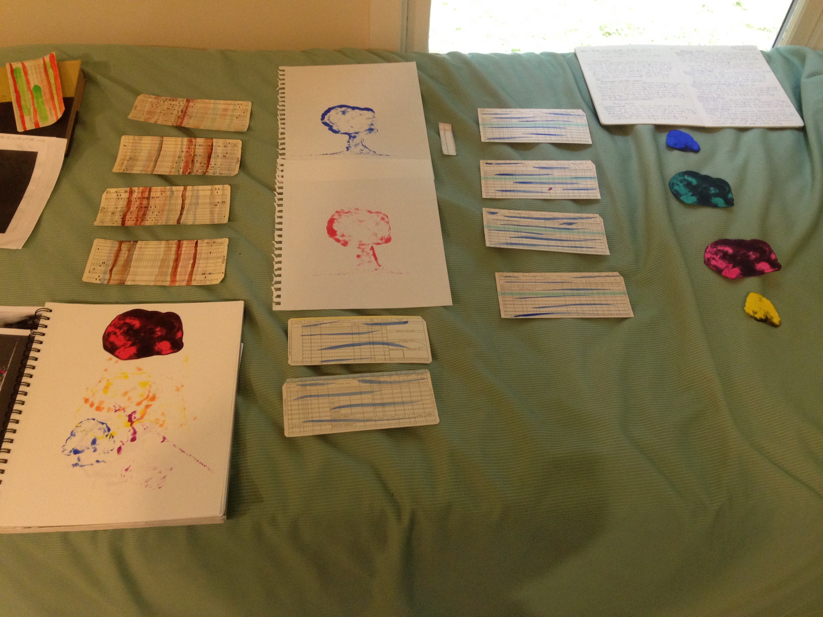 Punch cards, prints, and cutouts laid out on a bed.