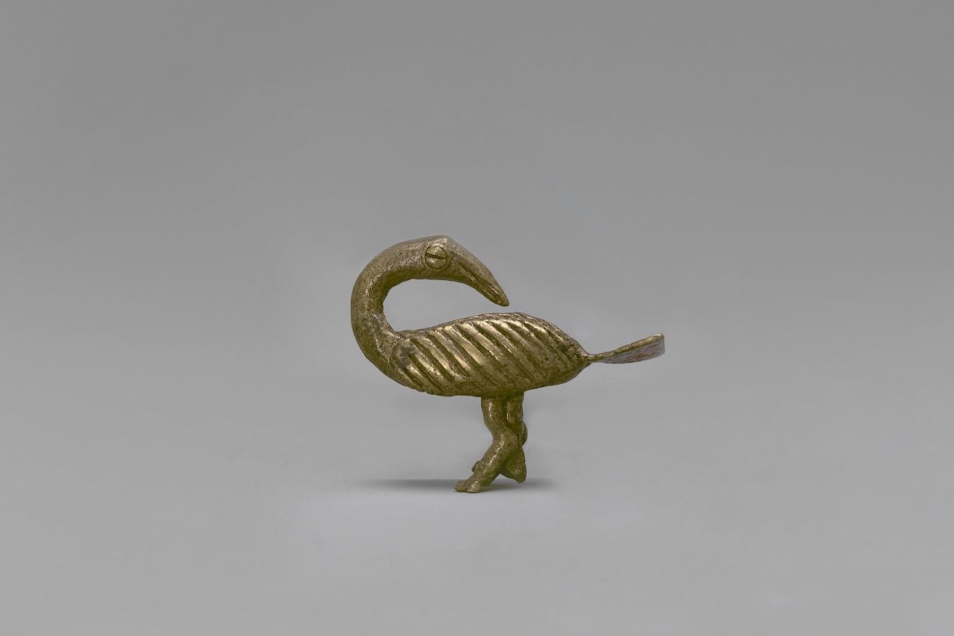 Gold Weight in Form of Sankofa Bird. Brass, 1 x 2 3/4 x 1 1/4 in.