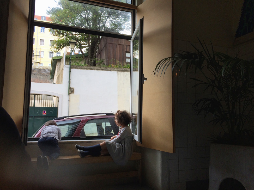 Photo of two children playing at an open window.