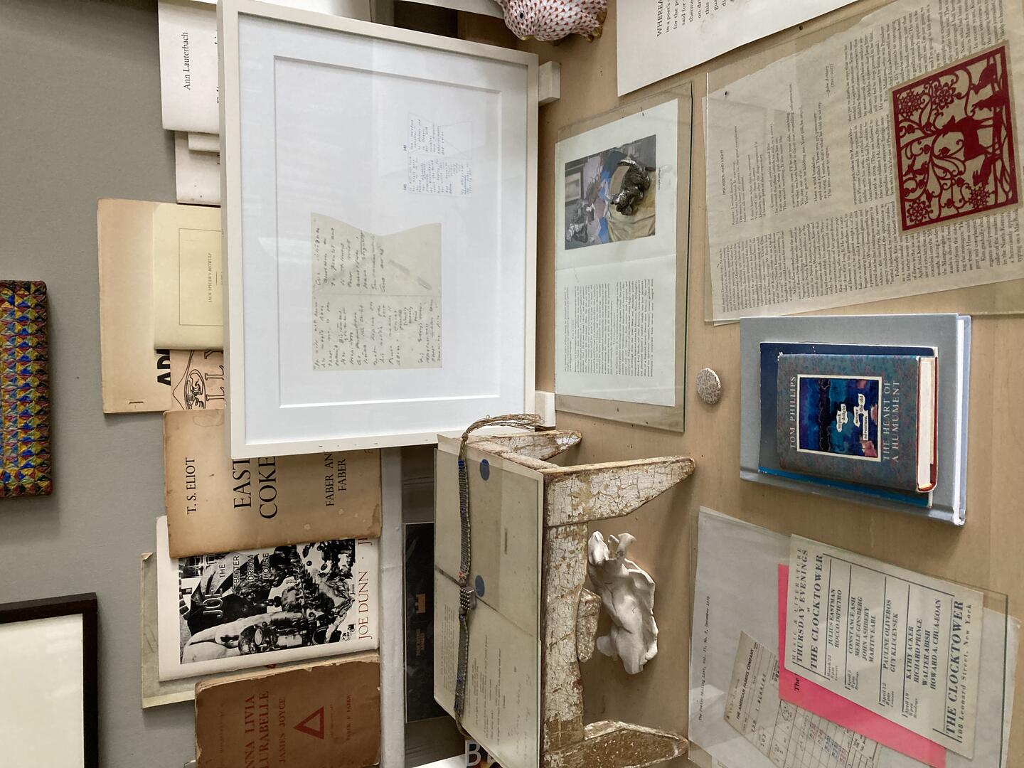 Color photo: A shelf in the background with books facing outward and a table with documents and books